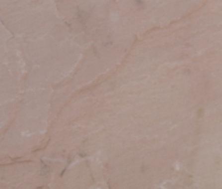 Jasnoróżowa powierzchnia z subtelnymi żyłkami i nierównościami, przypominająca polerowany kamień elewacyjny w zbliżeniu.