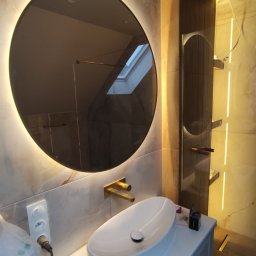 Oświetlenie za lustrem wraz z wodoodporną listwą LED pod prysznicem w zbliżonym odcieniu.  