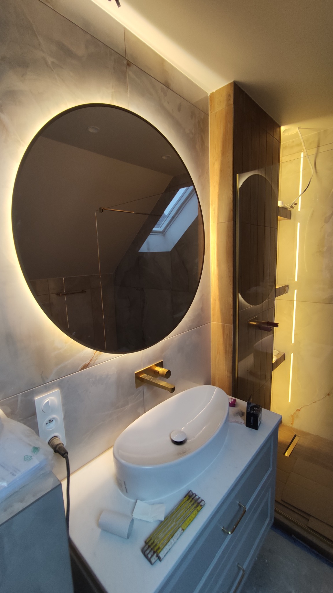 Oświetlenie za lustrem wraz z wodoodporną listwą LED pod prysznicem w zbliżonym odcieniu.