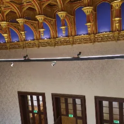 Wnętrze z bogato zdobionym sufitem w stylu gotyckim, oświetlenie szynowe z reflektorami punktowymi, trzy drewniane drzwi z zielonymi znakami ewakuacyjnymi.