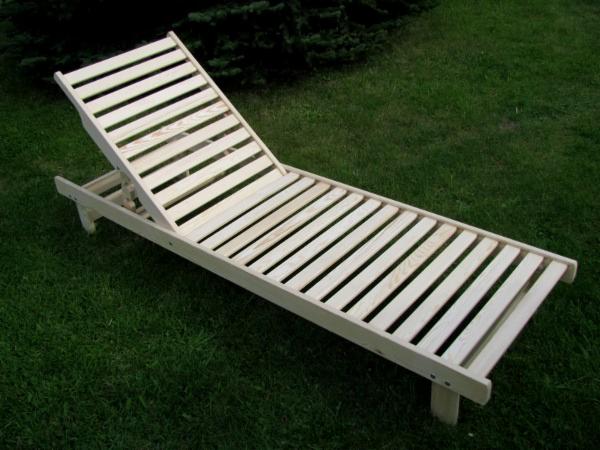 Drewniany leżak ogrodowy z regulowanym oparciem, ułożony na zielonej trawie, widok z boku.