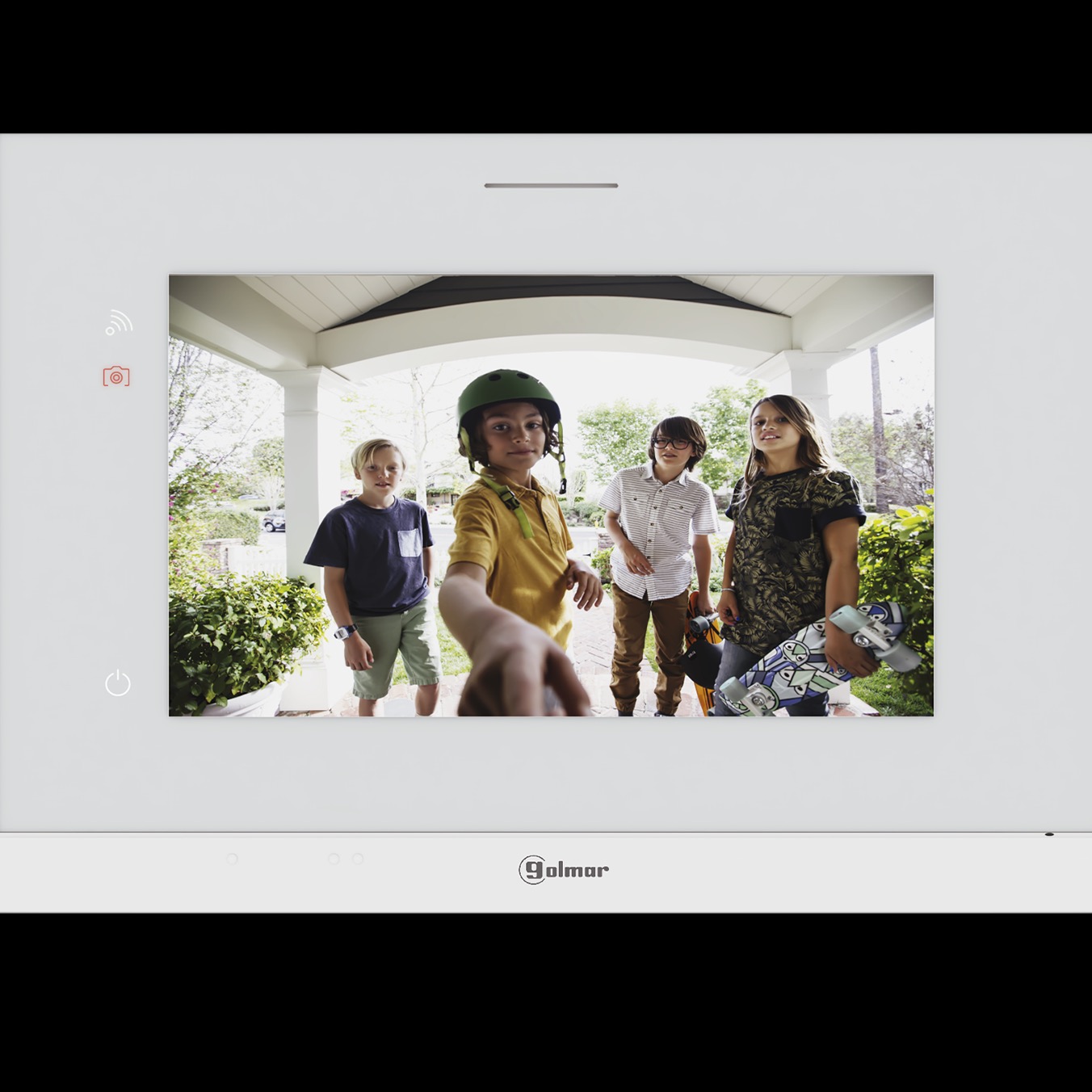 Ekran wideodomofonu Golmar wyświetlający czterech chłopców na werandzie domu, jeden z nich ma kask i trzyma deskorolkę.
