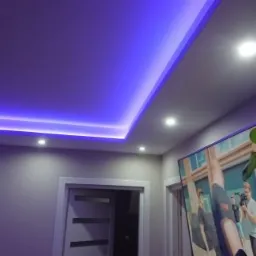 Nowoczesne oświetlenie sufitowe z listwą LED emitującą niebieskie światło, punktowe lampy halogenowe, szara ściana i drzwi w tle, fragment rośliny doniczkowej w prawym dolnym rogu.