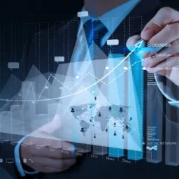 Mężczyzna w garniturze rysuje na interaktywnym wykresie wzrostu z naniesioną mapą świata, wskazując na sukces i strategie biznesowe.