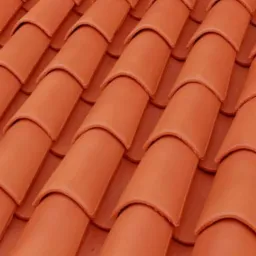Ułożone rzędami, ceramiczne elementy pokrycia dachowego w odcieniach terakoty, widoczne z bliska pod kątem.