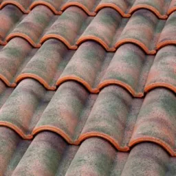 Ułożone dachówki ceramiczne w odcieniach zieleni, pomarańczy i brązu, widoczne z bliska pod kątem.