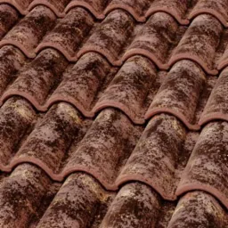 Ułożone dachówki ceramiczne w odcieniach brązu z widoczną patyną i drobnymi zabrudzeniami, ułożone w rzędach pod kątem.