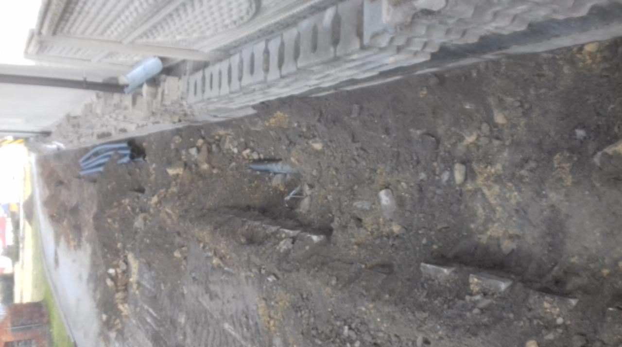 Wykop pod fundamenty budynku z widocznymi przewodami instalacyjnymi w ziemi.
