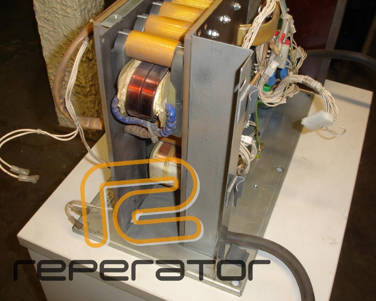 Wnętrze metalowej obudowy urządzenia elektrycznego z widocznymi transformatorami, kablami i złączami, serwisowane na białym stole.