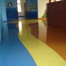 Błyszcząca, wielokolorowa podłoga z wykładziny PCV w korytarzu przedszkola, z motywem oceanu i zwierząt polarnych na ścianach.