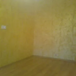 Pomalowane ściany na żółto z wzorem i drewniana podłoga w pokoju w Wałbrzychu. Widoczne gniazdko elektryczne.