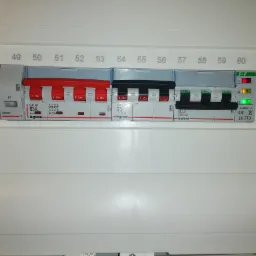 Rozdzielnica elektryczna Legrand z bezpiecznikami, część z nich w pozycji 'On', a część w pozycji 'Off', widoczne diody sygnalizacyjne.