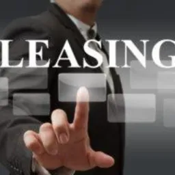 Mężczyzna w garniturze dotyka wirtualnego przycisku z napisem LEASING na interaktywnym ekranie dotykowym, z efektem głębi ostrości.