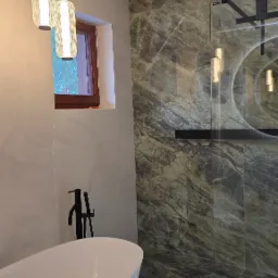 Nowoczesna łazienka z wolnostojącą białą wanną, czarną armaturą i marmurowymi płytkami z podświetleniem LED wzdłuż podłogi.