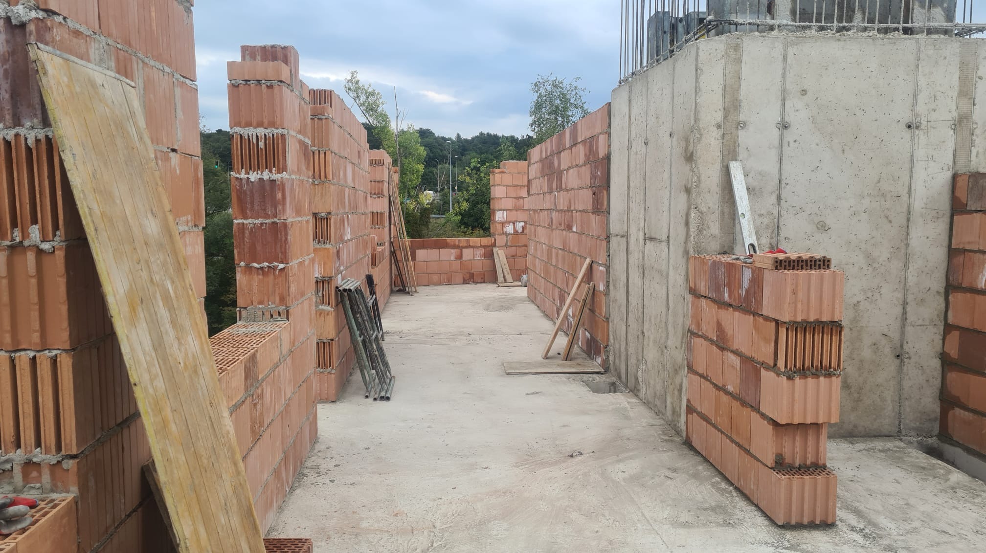 Wznoszenie ścian z pustaków ceramicznych na budowie domu w Krzczonowie, widoczne zbrojenie i betonowy fundament.