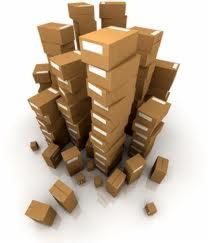 Stos kartonowych pudeł ułożonych w nierównomierne wieże, sugerujących transport i magazynowanie, w kontekście usług transportowych w Warszawie.