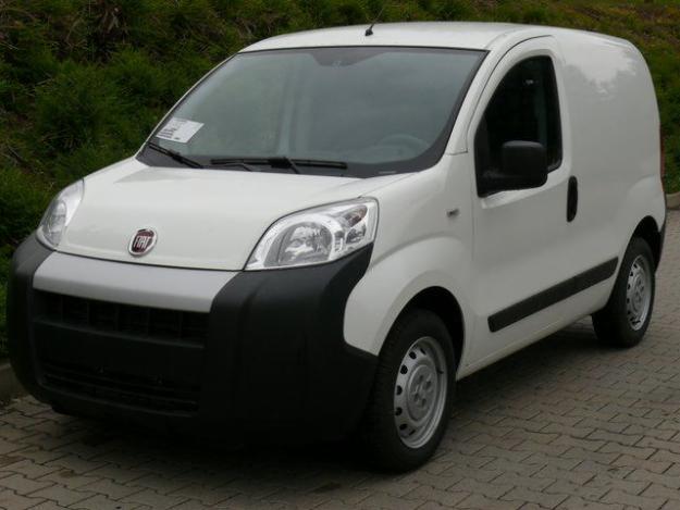 Biały samochód dostawczy Fiat Fiorino Cargo sfotografowany z przodu i boku na tle zieleni.
