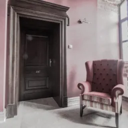 Ciemne, drewniane skrzydło z numerem 330 w ozdobnej futrynie, obok różowy fotel w pokoju z ceglanym oknem. Stylizowane wnętrze.