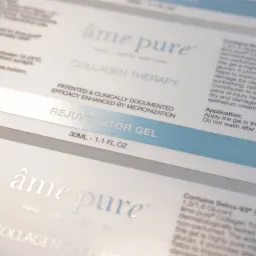 Zbliżenie na etykiety kosmetyków z serii kolagenowej, z wyraźnie widocznymi nazwami 'âme pure' i 'REJUVENATOR GEL', podkreślającymi innowacyjną formułę i pochodzenie z Paryża, Londynu i Nowego Jorku.