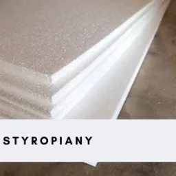 Stos białych płyt izolacyjnych z widoczną fakturą styropianu, ułożonych na sobie, z bliska.
