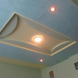 Ozdobny sufit podwieszany z oświetleniem punktowym i dekoracyjną fakturą w odcieniach błękitu. Widoczne fragmenty ścian w jasnych, pastelowych kolorach.