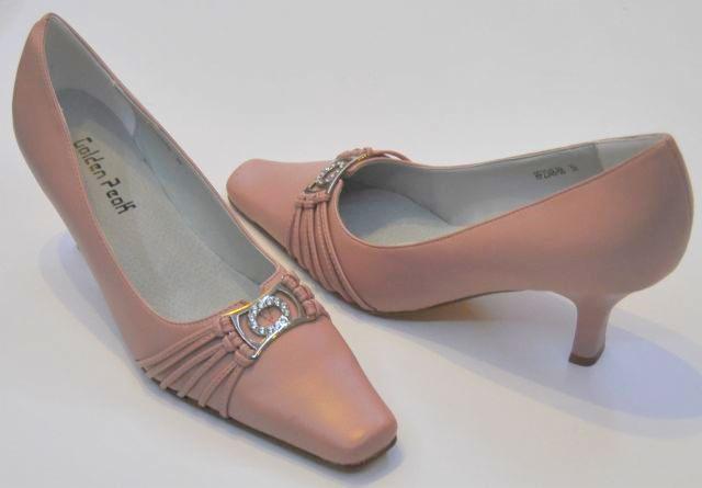 Para damskich, pudrowo-różowych czółenek z ozdobnymi, srebrnymi sprzączkami i niskim obcasem na białym tle.