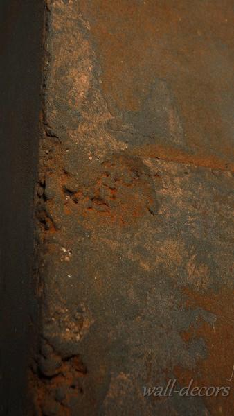 Nierówna, pomarańczowo-brązowa struktura ściany z widocznym narożnikiem. Szpachlowanie z efektem rdzy. Tekstura z bliska.