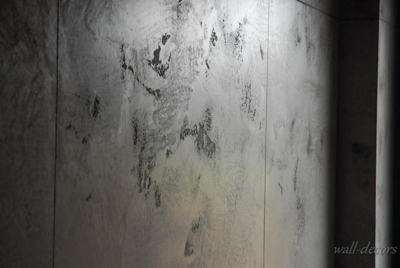 Dekoracyjna ściana w odcieniach szarości z nieregularną fakturą, imitująca surowy beton. Widoczne pionowe linie podziału i subtelne cieniowanie.