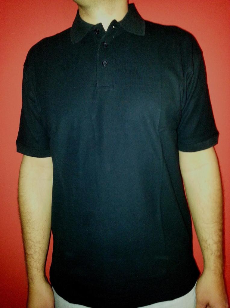 Mężczyzna w czarnej koszulce polo z trzema guzikami na tle czerwonej ściany, widoczne fragmenty ramion i szyi.