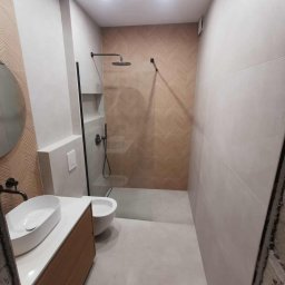 Usługi Remontowo-Budowlane Tip-Top Krzysztof Nidecki - Nowoczesna łazienka po remoncie: kabina walk-in z czarnymi detalami, umywalka nablatowa na drewnianej szafce, płytki w geometryczny wzór na ścianie.