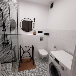 Usługi Remontowo-Budowlane Tip-Top Krzysztof Nidecki - Nowoczesna łazienka z kabiną prysznicową typu walk-in, umywalką na stelażu maszyny do szycia Singer i pralką Bosch. Biało-czarna kolorystyka, wzorzyste płytki podłogowe.