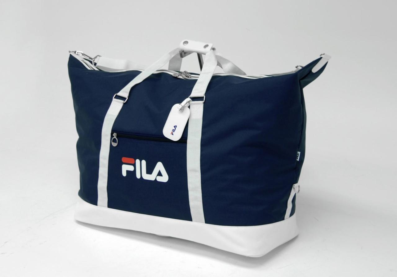 Granatowo-biała torba sportowa marki FILA z białymi uchwytami i zawieszką z logo, na białym tle.