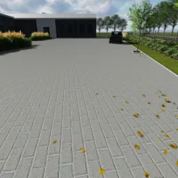 Szeroki, szary plac wyłożony kostką brukową w jodełkę, z rzadko rozsypanymi żółtymi liśćmi, obrzeża z zielenią i młodymi drzewami, w tle budynek przemysłowy i zaparkowany samochód.