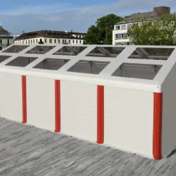 Biały namiot plenerowy z czerwonymi akcentami na tle miejskiej architektury i błękitnego nieba.