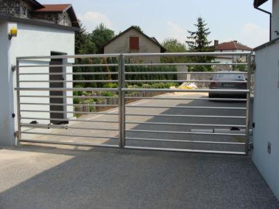 Nowoczesna, pozioma brama wjazdowa ze stali nierdzewnej, z automatycznym napędem, na tle domu i podjazdu.