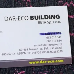 Wizytówka firmy budowlanej DAR-ECO BUILDING z logo w kształcie zielonego liścia z wrysowanym białym domem, umieszczona na wzorzystym, ciemnym tle.
