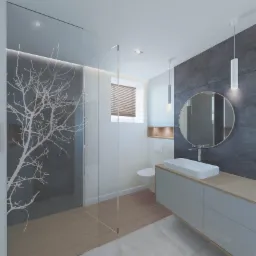 Nowoczesna łazienka z przeszkloną kabiną prysznicową z motywem drzewa, podwieszaną szafką z umywalką i okrągłym lustrem na tle szarej ściany z płytek, uzupełniona wiszącymi lampami.