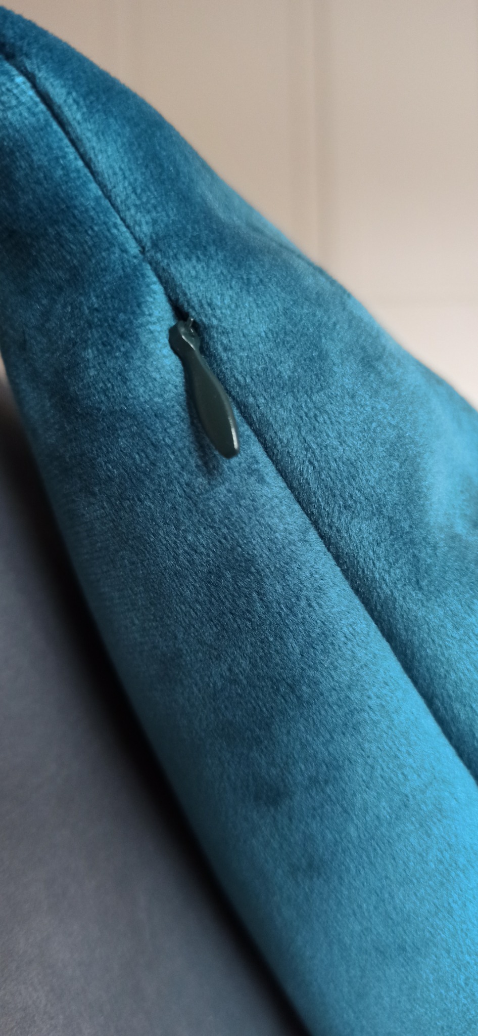 Zamknięcie błyskawiczne w poduszce dekoracyjnej z turkusowego weluru, widoczna faktura materiału.