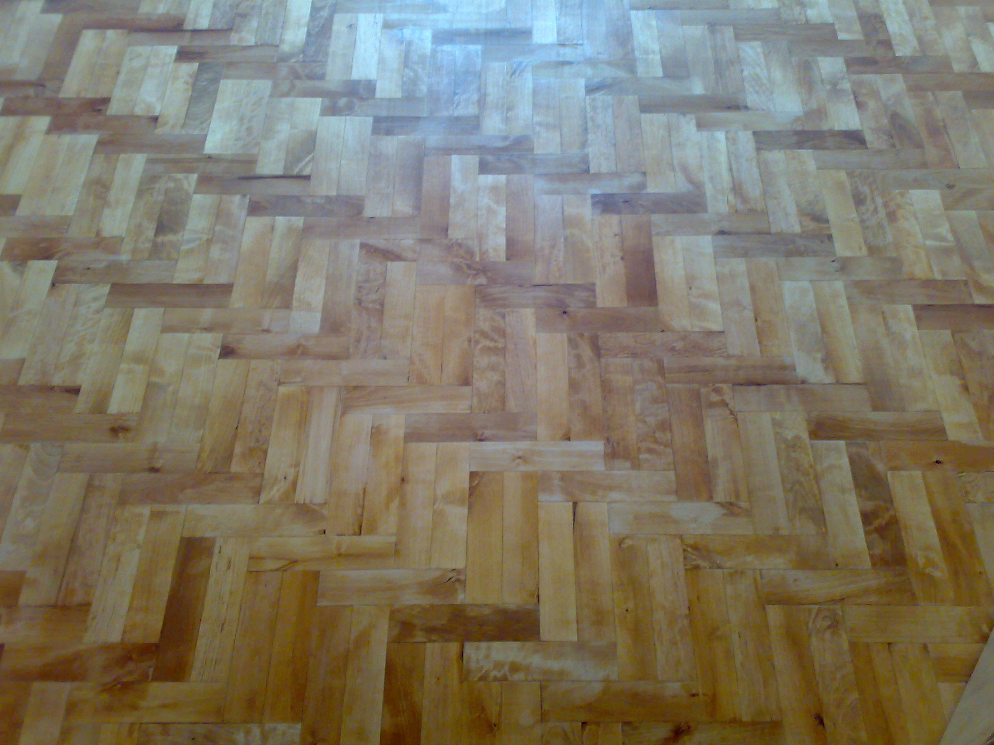 Ułożona w jodełkę podłoga z jasnego drewna, widoczne naturalne słoje i delikatny połysk.