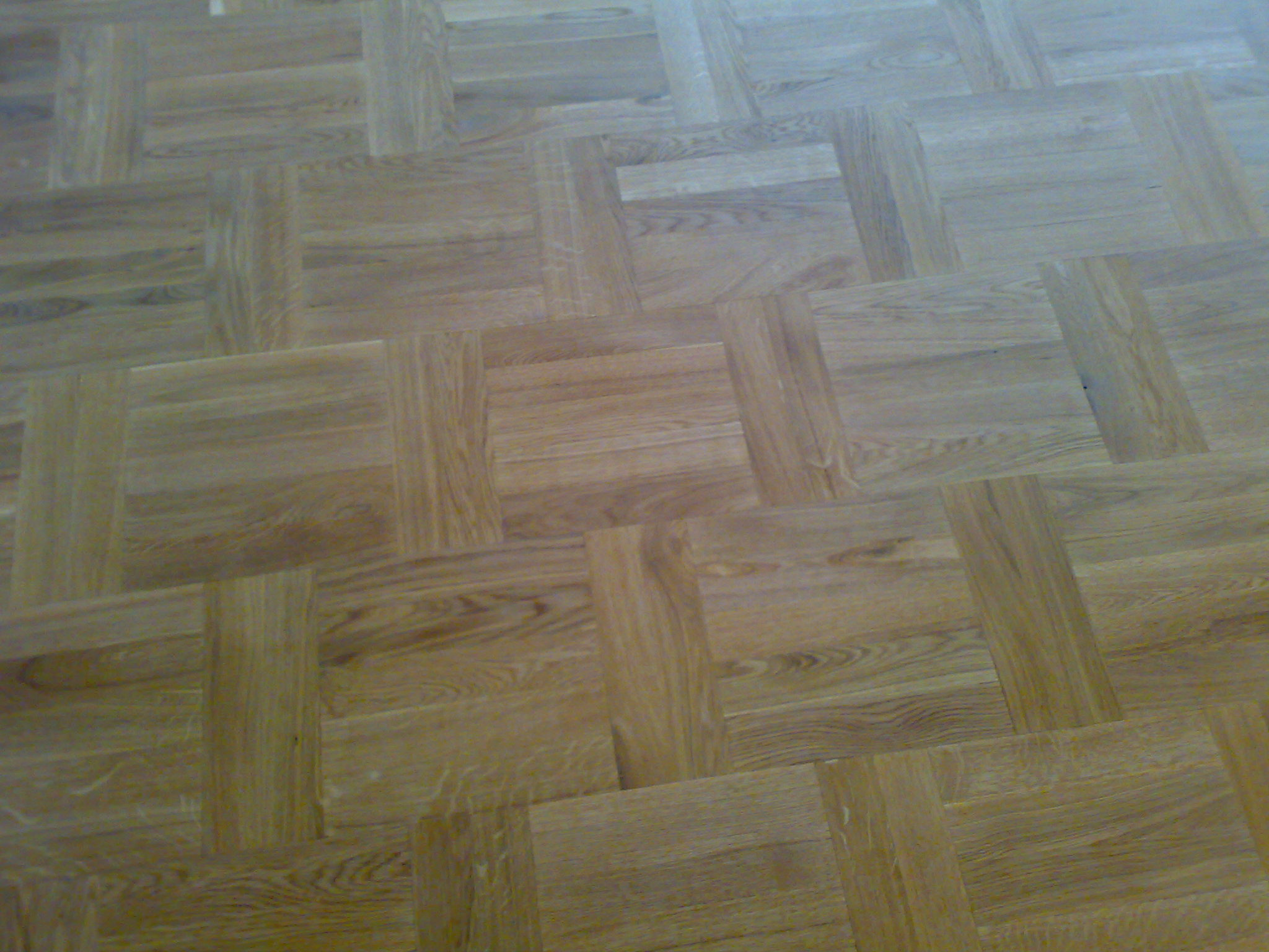 Parkiet dębowy ułożony we wzór szachownicy, świeżo po cyklinowaniu, widoczne naturalne usłojenie drewna i delikatny połysk lakieru.