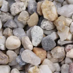 Drobny, zaokrąglony żwir o zróżnicowanej kolorystyce, od białego i beżowego po szary i brązowy, tworzący gęstą teksturę.