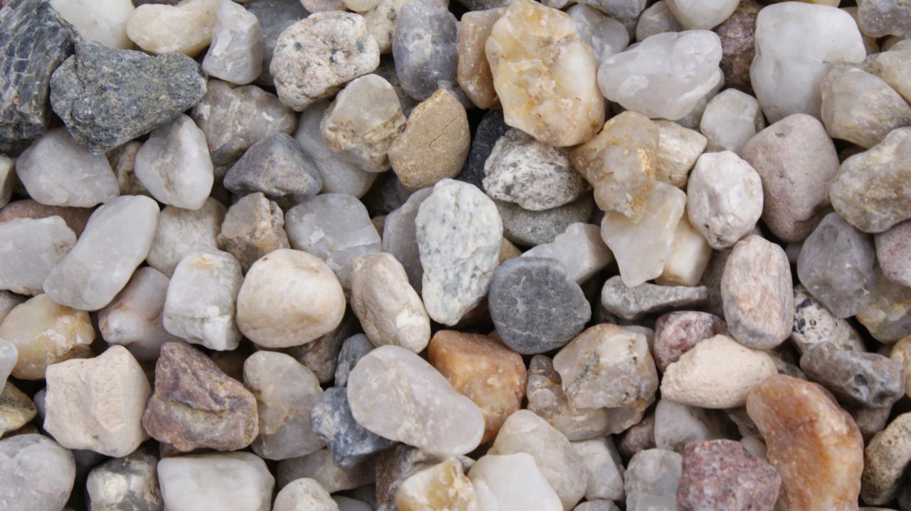 Drobny, zaokrąglony żwir o zróżnicowanej kolorystyce, od białego i beżowego po szary i brązowy, tworzący gęstą teksturę.