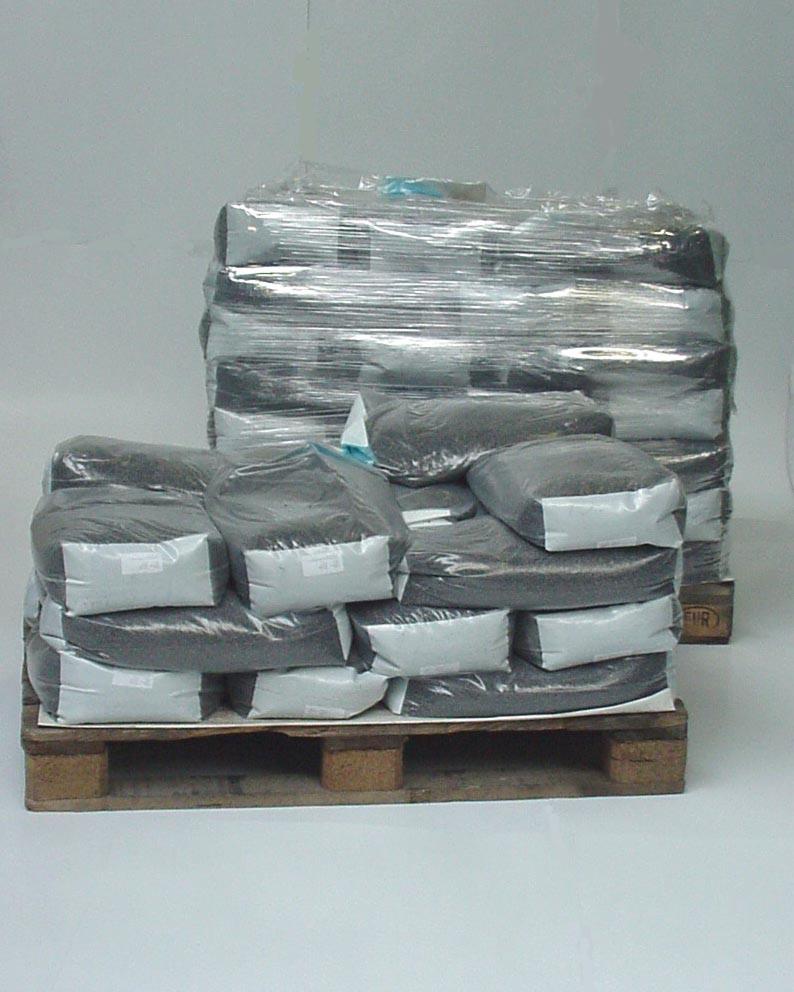 Dwa stosy worków z ciemnym kruszywem na drewnianych paletach, jeden owinięty folią stretch.