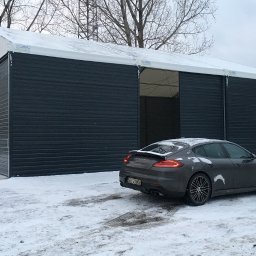 Przedsiębiorstwo Usług Produkcji i Handlu ECOPOL Ireneusz Zioła - Hala z płyt warstwowych w zimowej scenerii, z częściowo otwartymi przesuwnymi drzwiami i zaparkowanym obok samochodem Porsche Panamera. Widoczne ślady opon na śniegu.