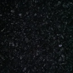 Ciemne, błyszczące bryłki węgla kamiennego, ułożone blisko siebie, tworzące jednolitą teksturę.