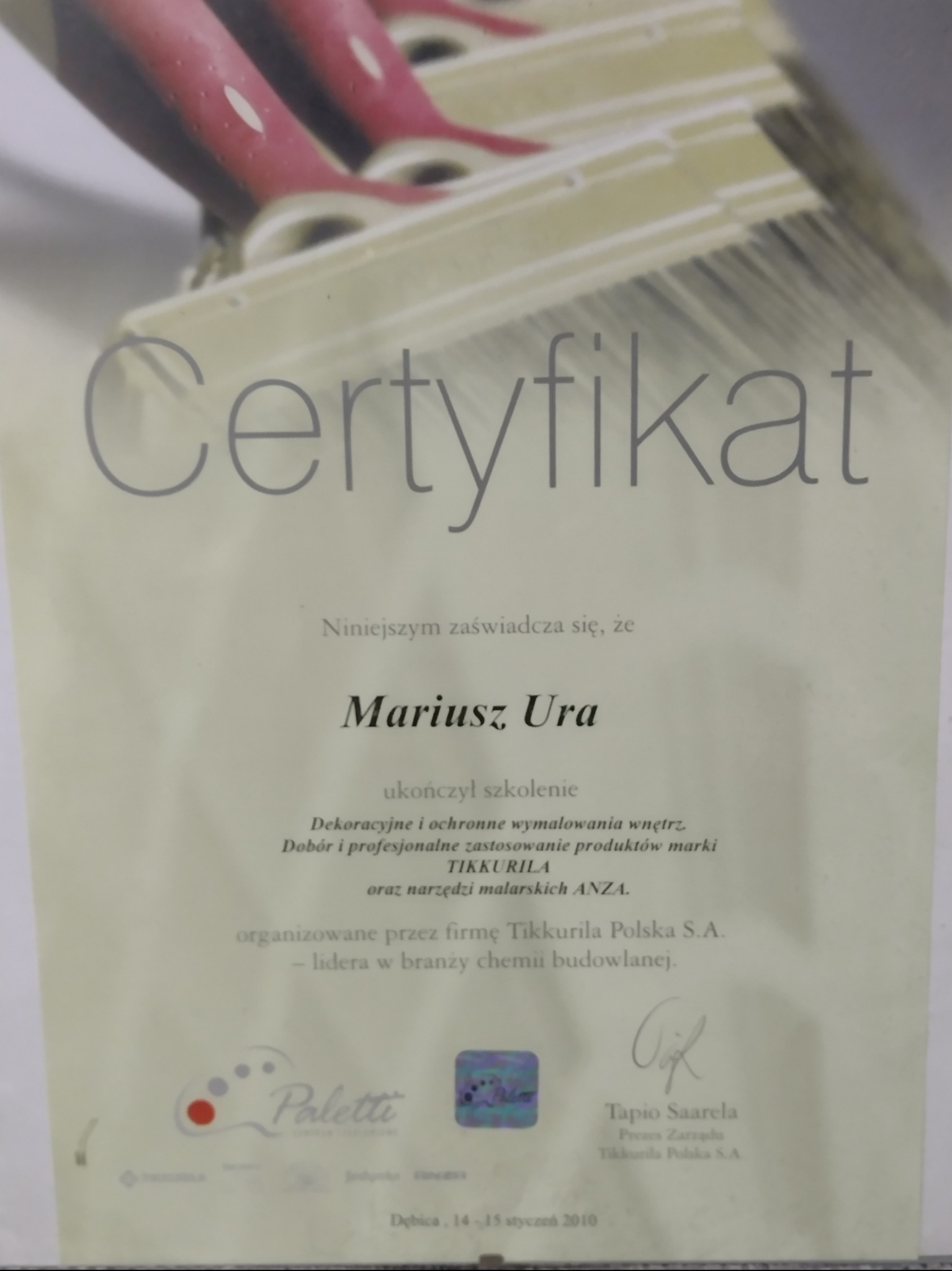 Certyfikat ukończenia szkolenia z dekoracyjnych wymalowań wnętrz, wydany przez Tikkurila Polska S.A., z widocznymi pędzlami malarskimi w tle. Dębica, 2010.