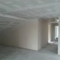 Pok&oacute;j po montażu płyt gipsowo-kartonowych na poddaszu, z widocznymi łączeniami i przewodami wystającymi z sufitu. Przygotowanie do szpachlowania i malowania.