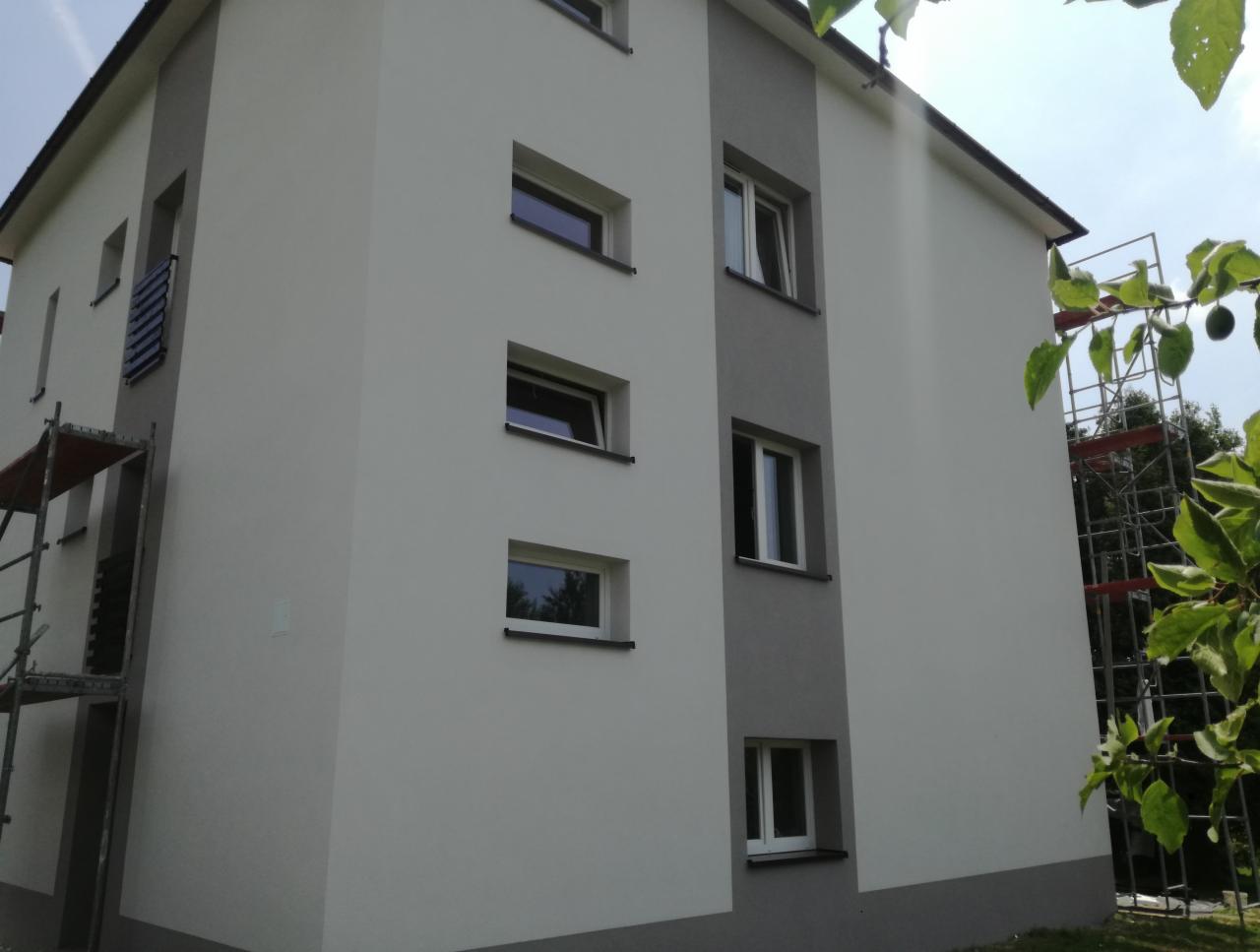 Elewacja budynku po remoncie z widocznymi rusztowaniami i nowymi obróbkami blacharskimi dachu.