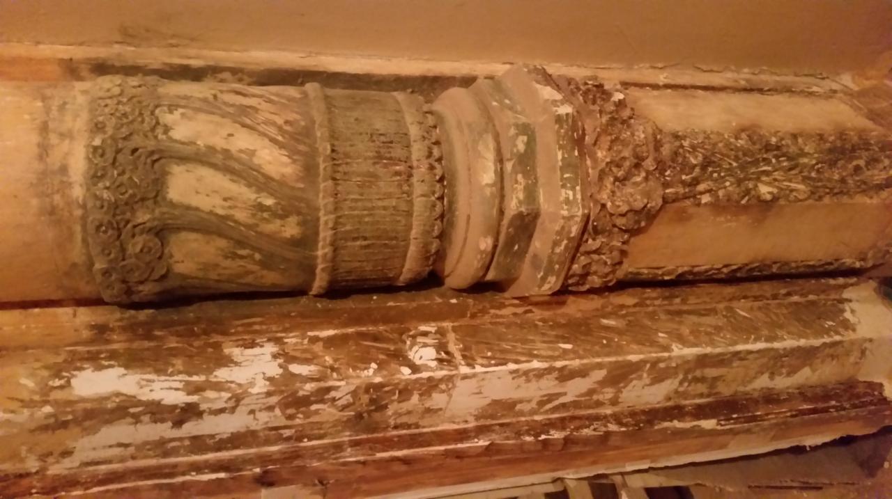 Fragment zabytkowej, zdobionej kolumny z widocznymi śladami zużycia i odchodzącą farbą, ukazujący detale architektoniczne wymagające renowacji.