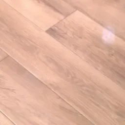 Ułożone panele podłogowe w odcieniach jasnego drewna, widoczne połączenia między panelami i delikatny połysk.